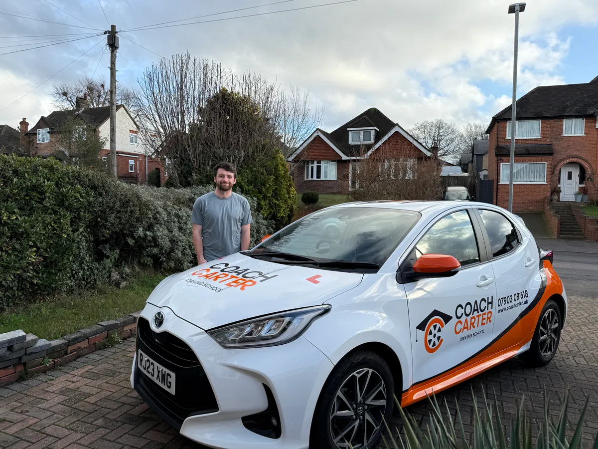 Fraser from CoachCarter standing next to the CoachCarter driving school car